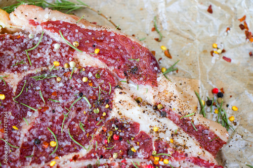 Raw beef meat on the table, spices and Rosemary, Rib eye steak ingredients. Pepper and coars salt. photo