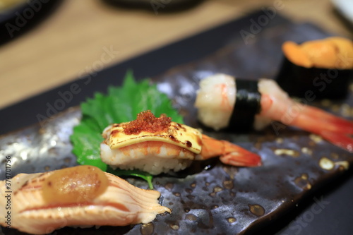 Shrimp sushi topped with grilled cheese and topped with orange roe On a traditional Japanese plate in a Japanese restaurant