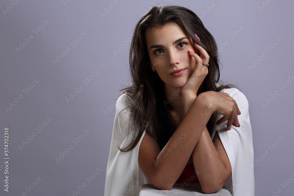 Fototapeta premium Beautiful girl in a white Cape on a gray background