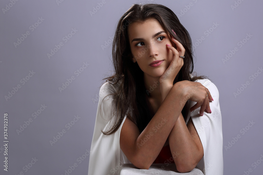 Naklejka premium Beautiful girl in a white Cape on a gray background