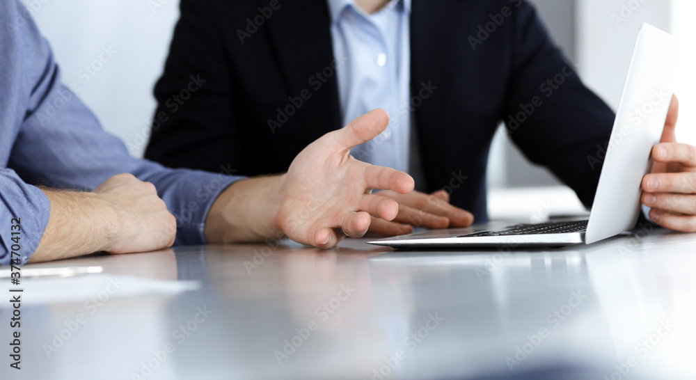 Fototapeta premium Business people using laptop computer while working together at the desk in modern office. Unknown businessman or male entrepreneur with colleague at workplace. Teamwork and partnership concept