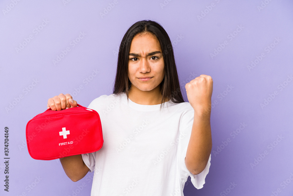 Young indian woman holding an aid kid isolated showing fist to camera, aggressive facial expression. Young indian woman holding an aid kid isolated showing fist to camera, aggressive facial expression.