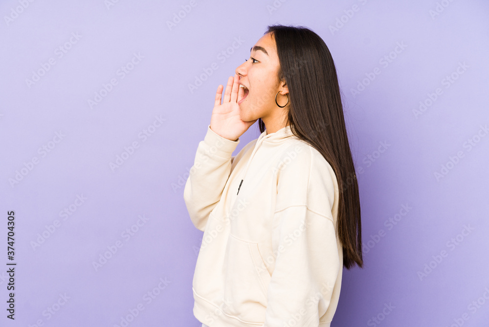 Young woman isolated on a purple background shouting and holding palm near opened mouth. Young woman isolated on a purple background shouting and holding palm near opened mouth.