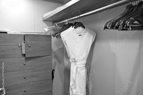 Bathrobe and wooden hangers inside closet or walk-in wardrobe of suite category stateroom or cabin on luxury cruiseship or cruise ship liner photo