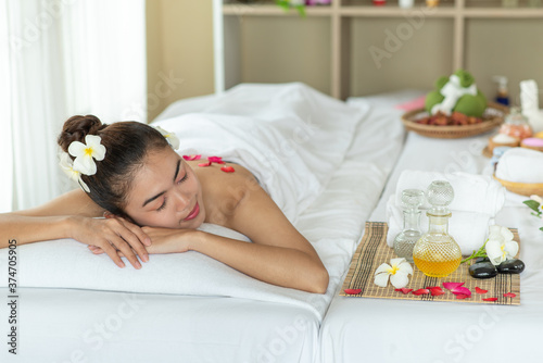 Beautiful Asian woman lying down on massage bed relaxing in spa salon