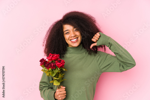 Young afro woman holding a roses isolated Young afro woman holding a rosesfeels proud and self confident, example to follow.