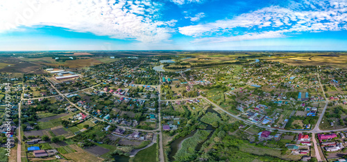 houses, streets and a stream bed, overgrown with reeds, in the village of Sergievskaya on a hot sunny day in midsummer - a large aerial drone panorama