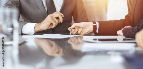 Unknown business people working together at meeting in modern office, close-up. Businessman and woman with colleagues or lawyers discussing contract at negotiation