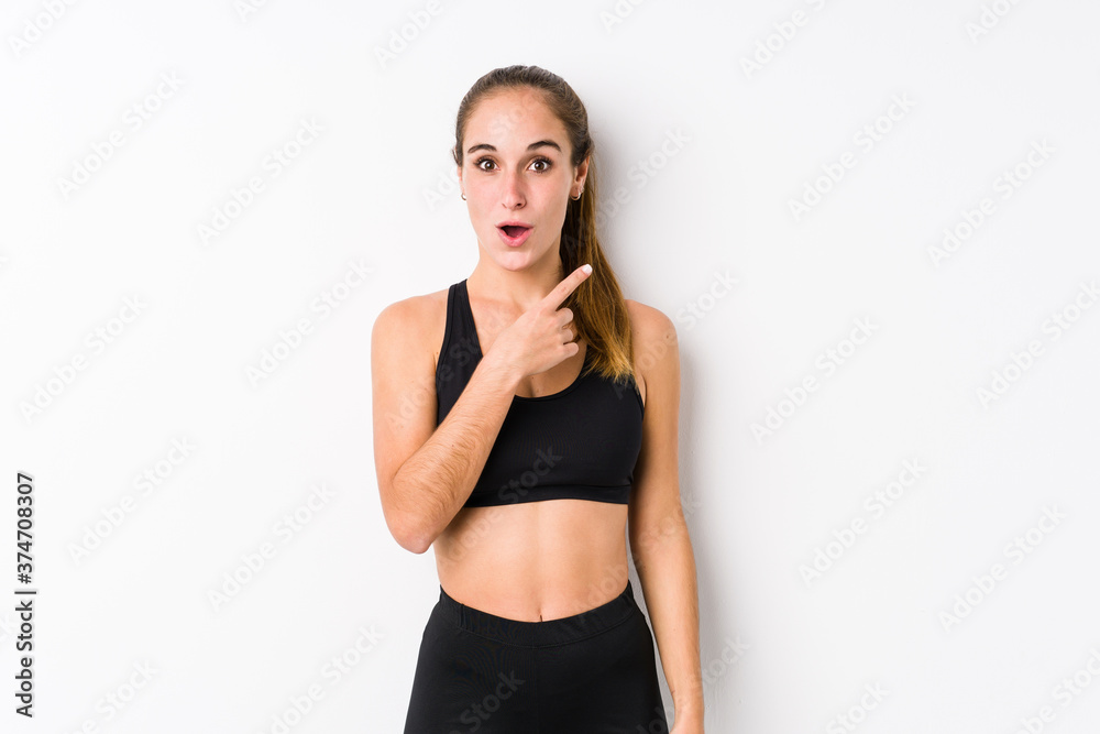 Young caucasian fitness woman posing in a white background pointing to the side Young caucasian fitness woman posing in a white background pointing to the side