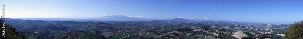 Panorama of the countryside of central Italy with the Sibillini mountains in the background and cultivated fields as far as the eye can see, clear sky without clouds 