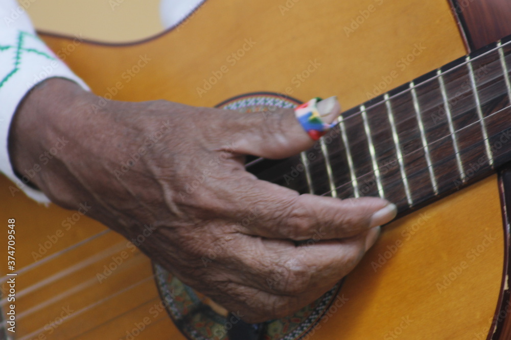 fingers of the hand playing a string instrument made of wood guitar