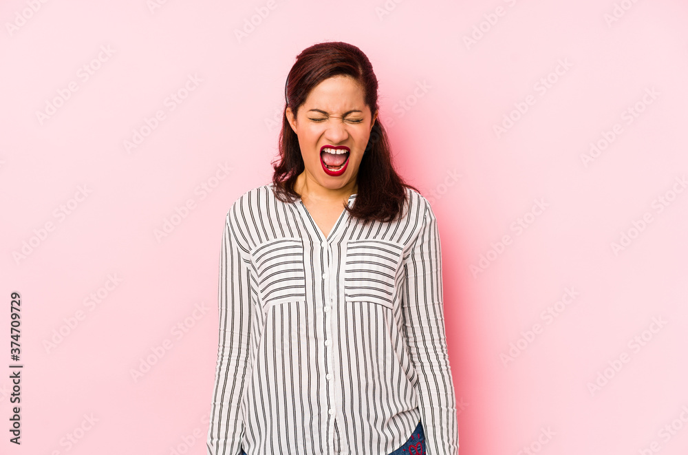 Middle age latin woman isolated on a pink background screaming very angry and aggressive. Middle age latin woman isolated on a pink background screaming very angry and aggressive.