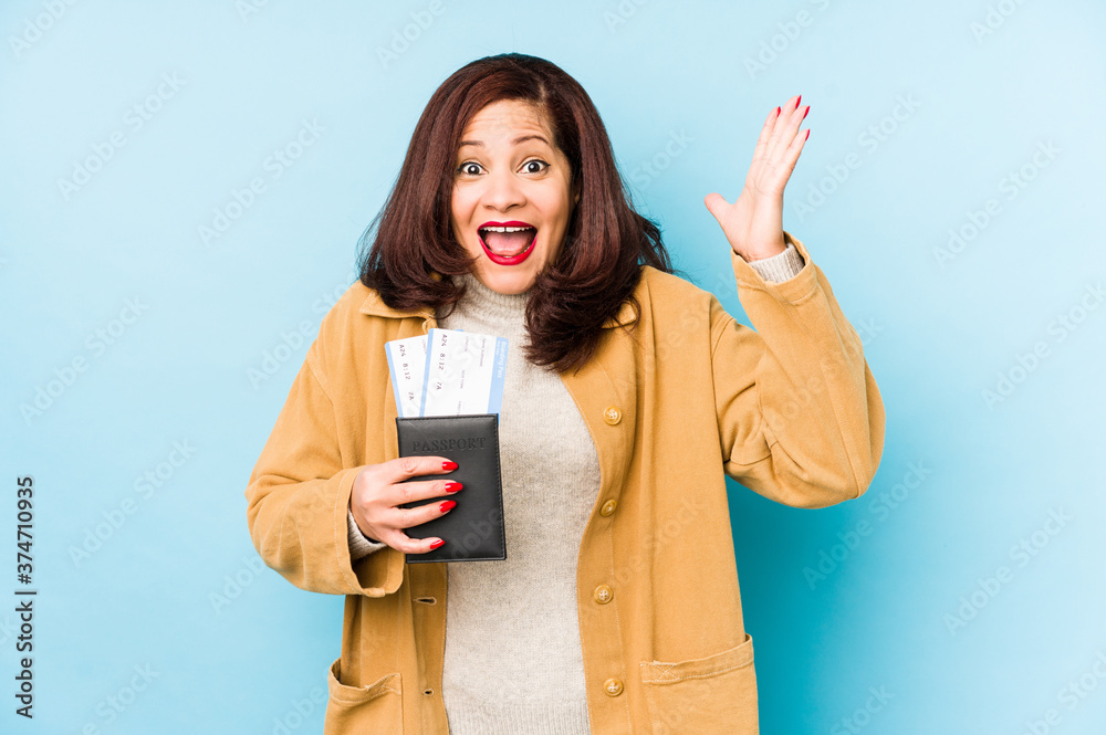 Middle age latin woman holding a passport isolated receiving a pleasant surprise, excited and raising hands. Middle age latin woman holding a passport isolated receiving a pleasant surprise, excited and raising hands.