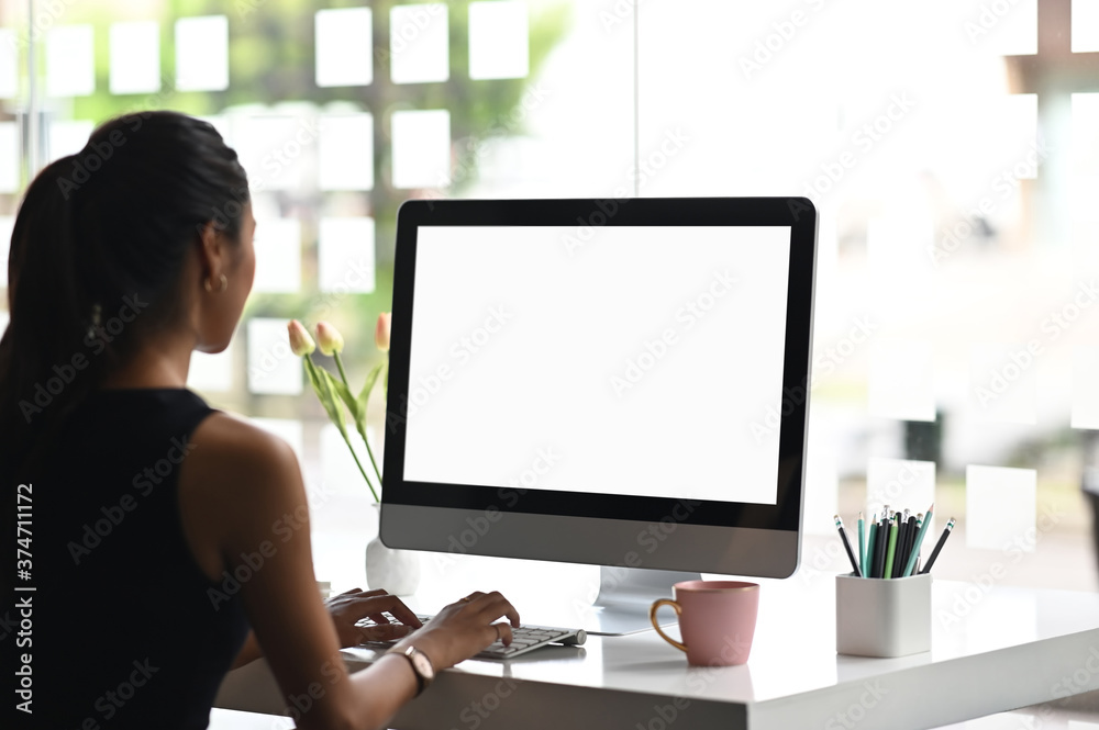 A woman is using a mockup computer with empty screen on modern workspace. A woman is using a mockup computer with empty screen on modern workspace.