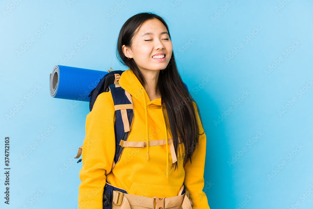 Young chinese backpacker woman isolated relaxed and happy laughing, neck stretched showing teeth. Young chinese backpacker woman isolated relaxed and happy laughing, neck stretched showing teeth.
