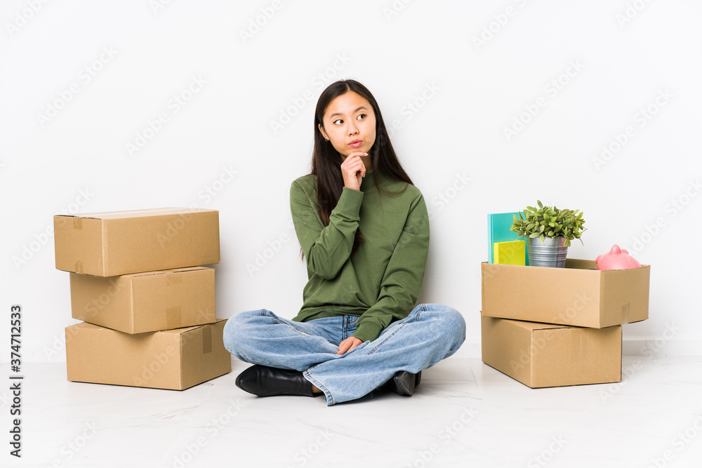 Young chinese woman moving to a new home looking sideways with doubtful and skeptical expression. Young chinese woman moving to a new home looking sideways with doubtful and skeptical expression.