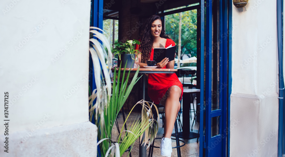 Obraz premium Content woman sitting at table with book in cafe