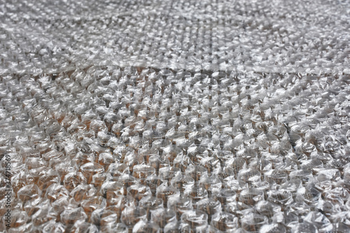 An abstract image of plastic bubble wrap packing material on a wooden table. 