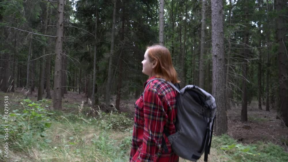 girl with a backpack is walking through the forest girl with a backpack is walking through the forest