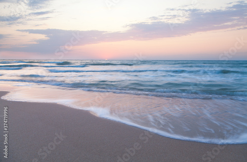 Waves washing the sandy sea beach at sunrise. © Uilia