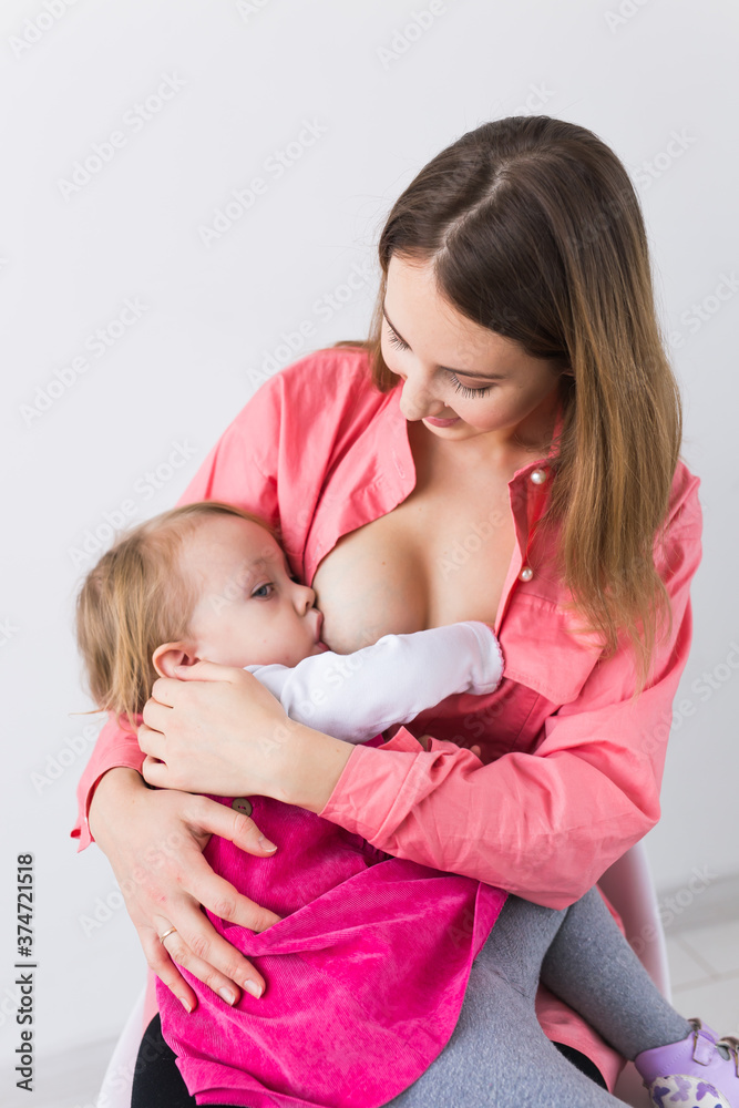 Lactation and motherhood concept - Young beautiful mother holding breastfeeding baby sitting on chair. Lactation and motherhood concept - Young beautiful mother holding breastfeeding baby sitting on chair.