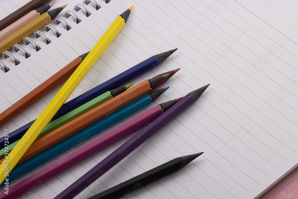 Multicolor blackwood pencils are laid out on a spiral notebook. Back to school, copy space Multicolor blackwood pencils are laid out on a spiral notebook. Back to school, copy space