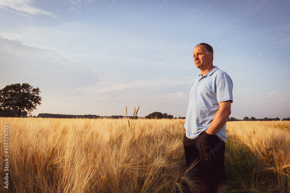 Landwirtschaft - Agrarpolitik, nachdenklicher Landwirt mit seinem Sohn im Getreidefeld Landwirtschaft - Agrarpolitik, nachdenklicher Landwirt mit seinem Sohn im Getreidefeld