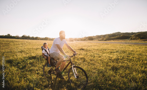 Father and his son cycling together outdoors, copy space