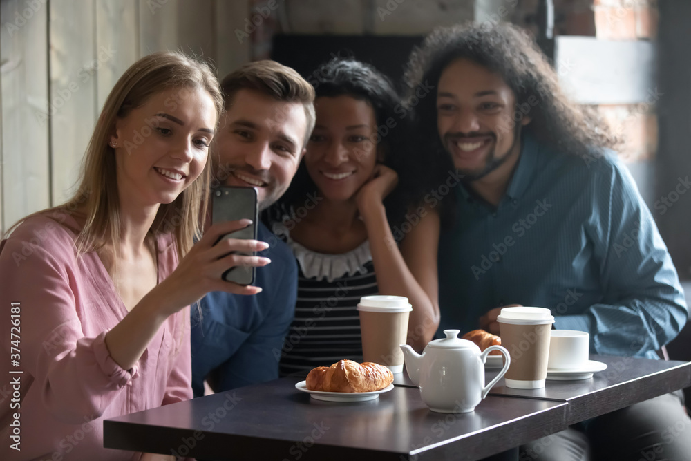 Happy diverse people taking selfie for social network, sitting at table in cafe, smiling young woman holding smartphone, photographing, posing for photo with friends, vlogger recording video Happy diverse people taking selfie for social network, sitting at table in cafe, smiling young woman holding smartphone, photographing, posing for photo with friends, vlogger recording video