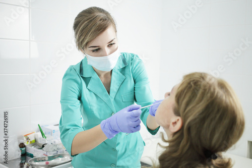 A nurse wearing a medical mask takes a swab from a patient's nose.