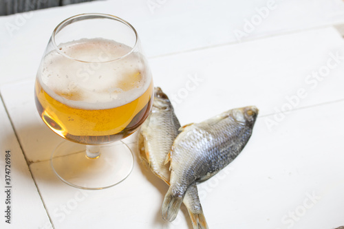 A glass of beer. Dried river fish lies nearby. photo