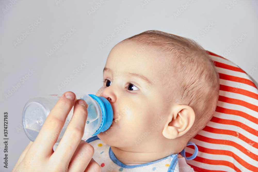 Giving to drink water baby from bottle, closeup