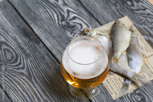 A glass of beer. Dried river fish lies nearby. photo