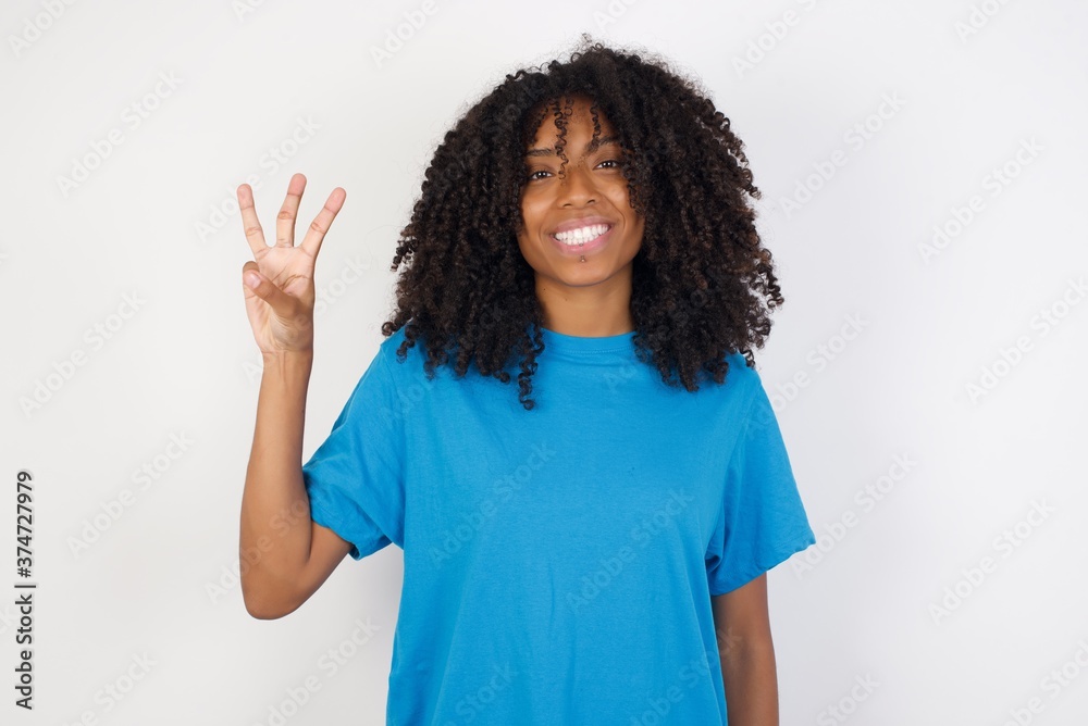 Young african woman with curly hair wearing casual blue shirt over white background showing and pointing up with fingers number three while smiling confident and happy.