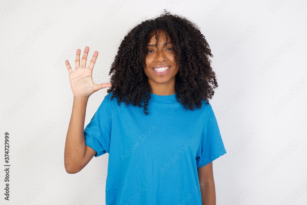Young african woman with curly hair wearing casual blue shirt over white background showing and pointing up with fingers number five while smiling confident and happy. Young african woman with curly hair wearing casual blue shirt over white background showing and pointing up with fingers number five while smiling confident and happy.