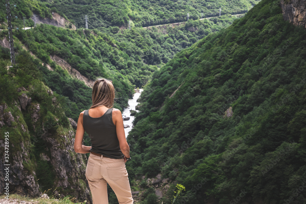 Blonde girl looks at a beautiful gorge in kabardino-balkaria republic. Blonde girl looks at a beautiful gorge in kabardino-balkaria republic.