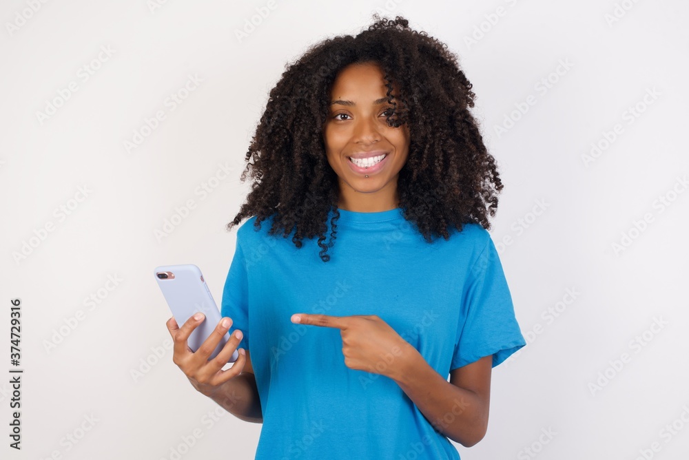 Portrait of Young african woman with curly hair wearing casual blue shirt holding in hands showing new cell, Portrait of Young african woman with curly hair wearing casual blue shirt holding in hands showing new cell,