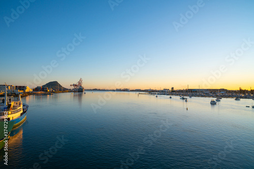 Tauranga harbour at sunrise with port facilities and landmark Mount Maunganui on golden horizon © Brian Scantlebury
