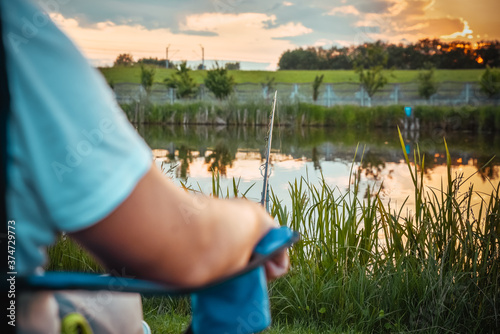 Young man fishing on lake at sunset enjoying hobby. Outdoor, activity. Narrow focus. photo