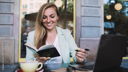 Young woman with notebook and laptop in cafe