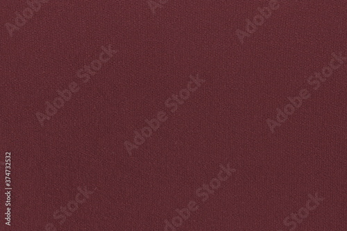 The texture of a simple knitted cotton fabric on the wrong side with a clear interweaving of maroon threads. Coarse plain cloth, burlap.