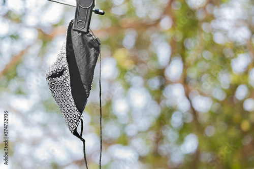 The picture of cloth mask hanging after washing outside to dry by sunlight before reuse course. The reason is to save money during The Coronavirus disease (COVID 19) effect.