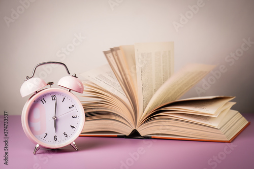 Time to school. Detail close up of the old pink vintage alarm. In the background are old book.