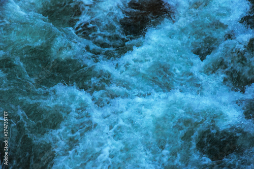 Raging water in the river. The natural texture of the seething water in the river. Natural background of mountain river water.