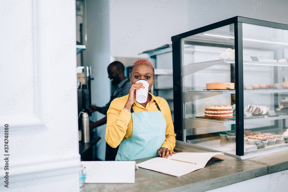 Fototapeta premium Black barista drinking coffee in pastry shop