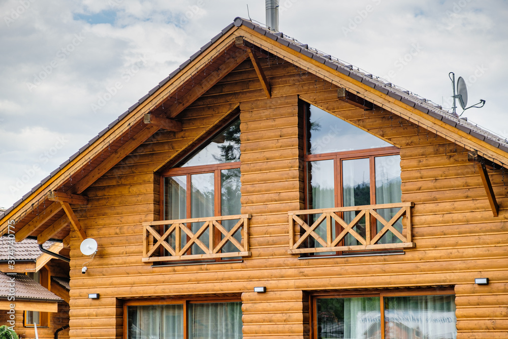  Modern wooden house with big windows and balcony. Concept of building of family houses, pensions or cottages in the countryside. Building of houses under the key