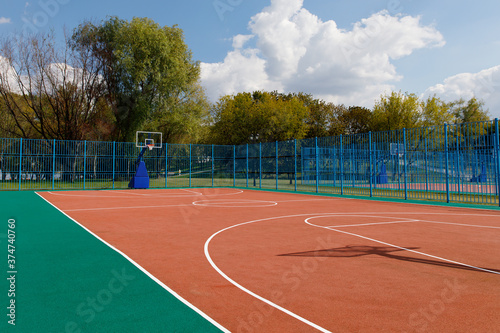 Basketball playground without people, outdoor sports ground, park, sunny weather, trees, sky.