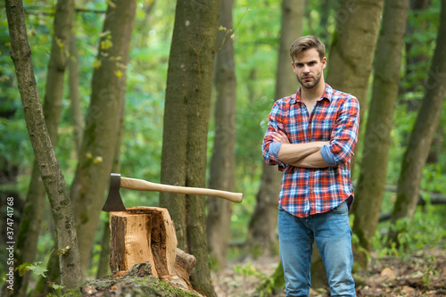 Good looking man posing with axe, nature