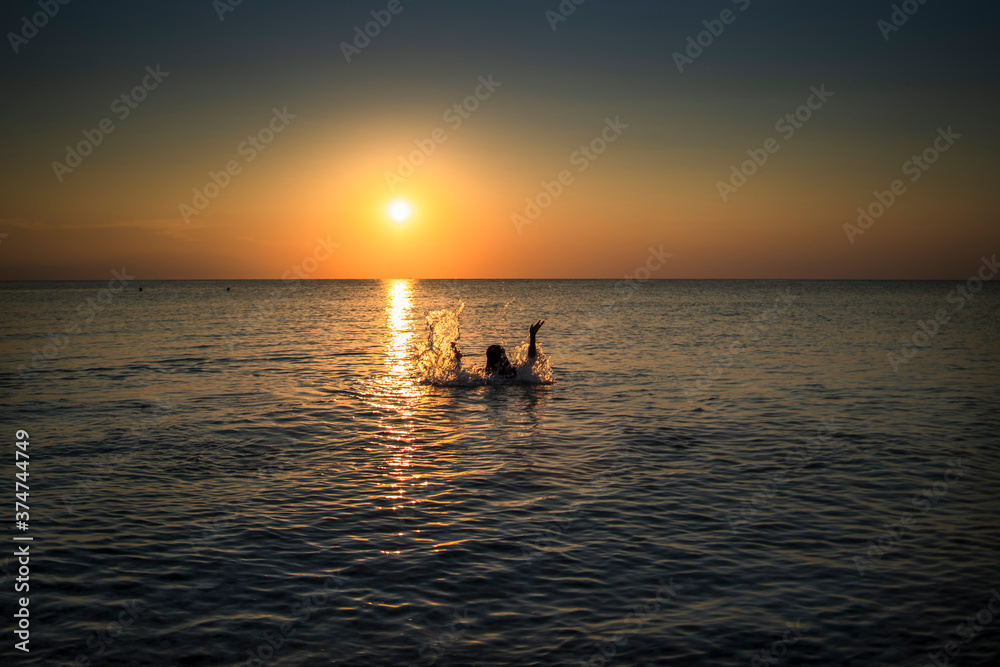 a girl bathing in the sea at sunset