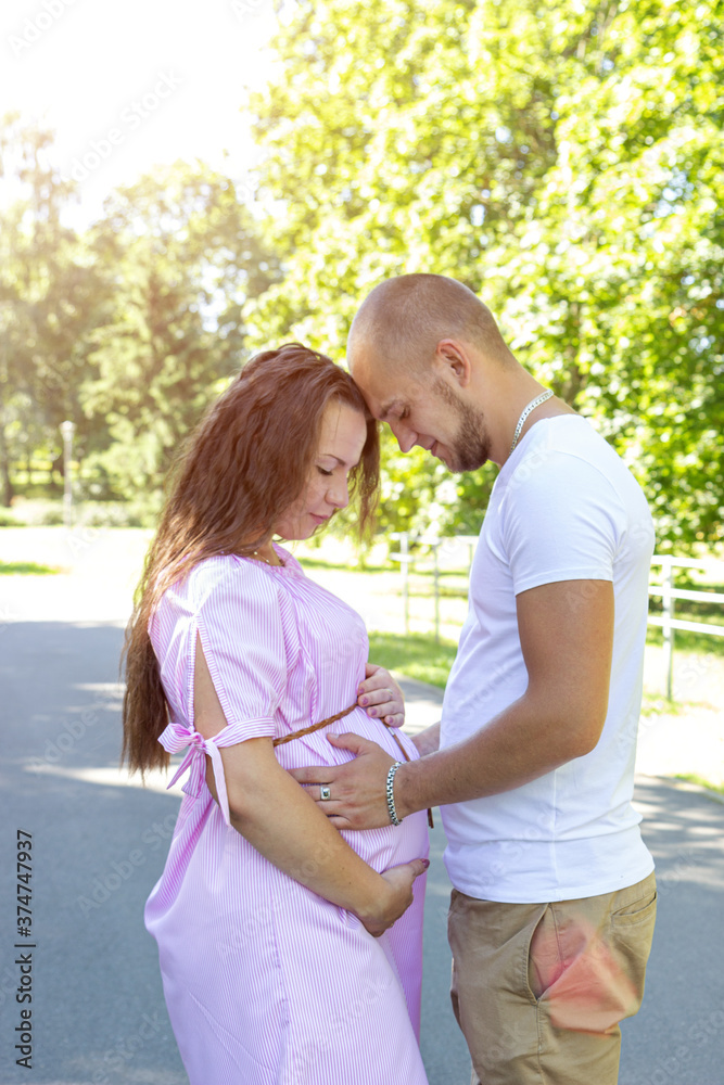 Fototapeta premium Young happy pregnant couple hugging in nature. Concept of love, relationship, marriage, family creation, pregnancy, parenting